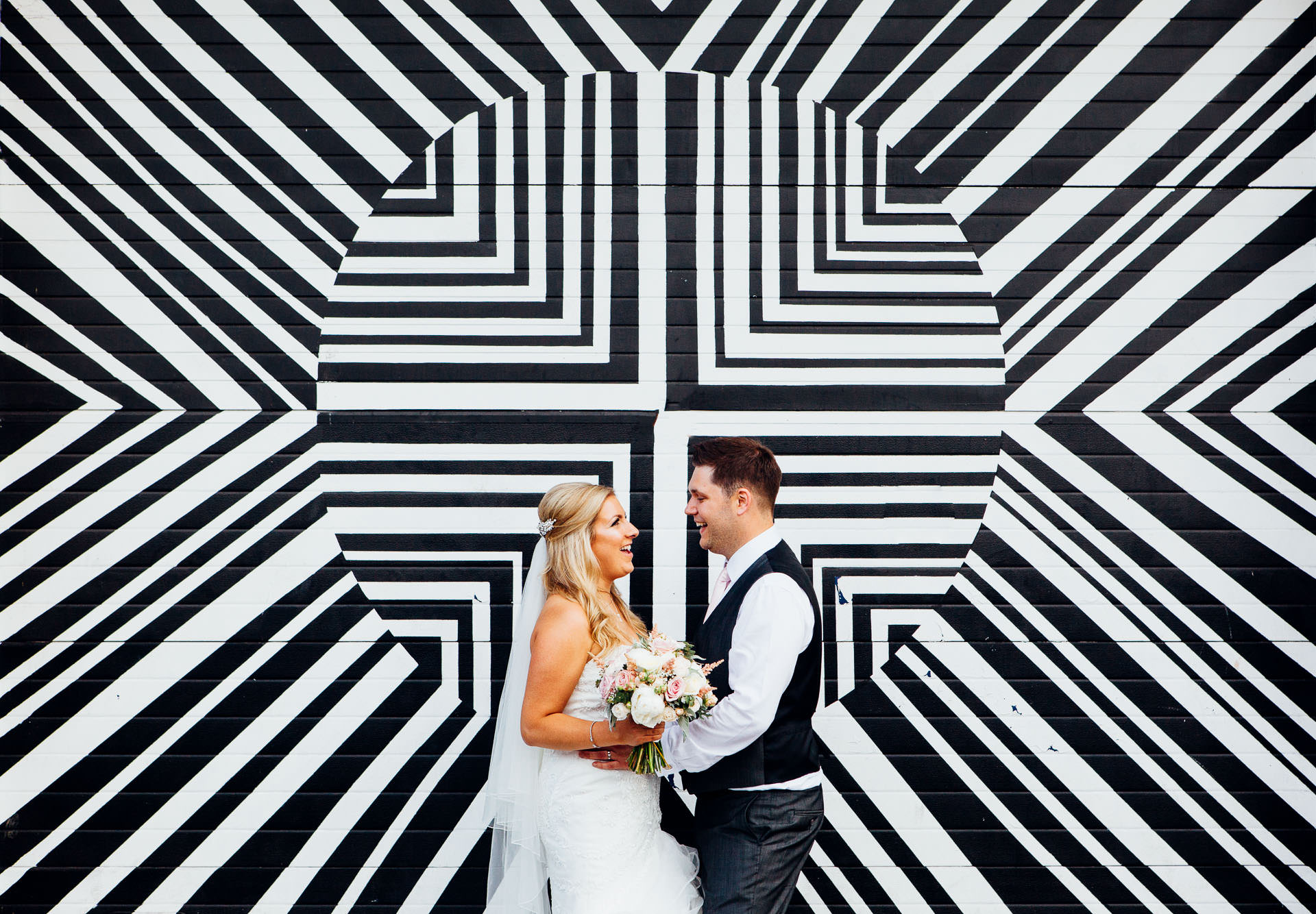 Bride and groom at Fazeley Studios wedding in front of a black and white wall of geometric shapes